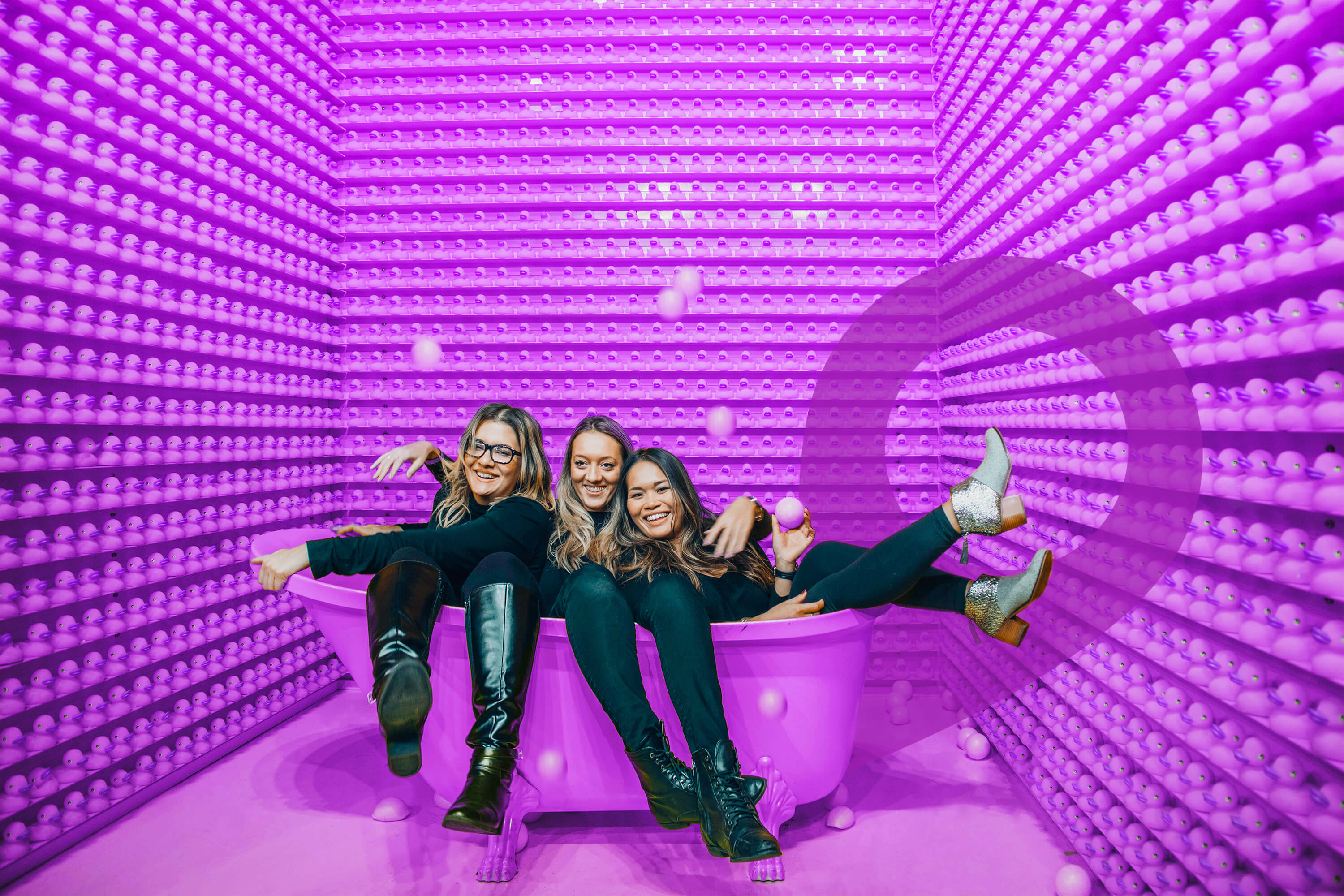 Group of friends laughing in a colorful purple bathtub photo booth, a fun and Instagram-worthy date idea in Toronto